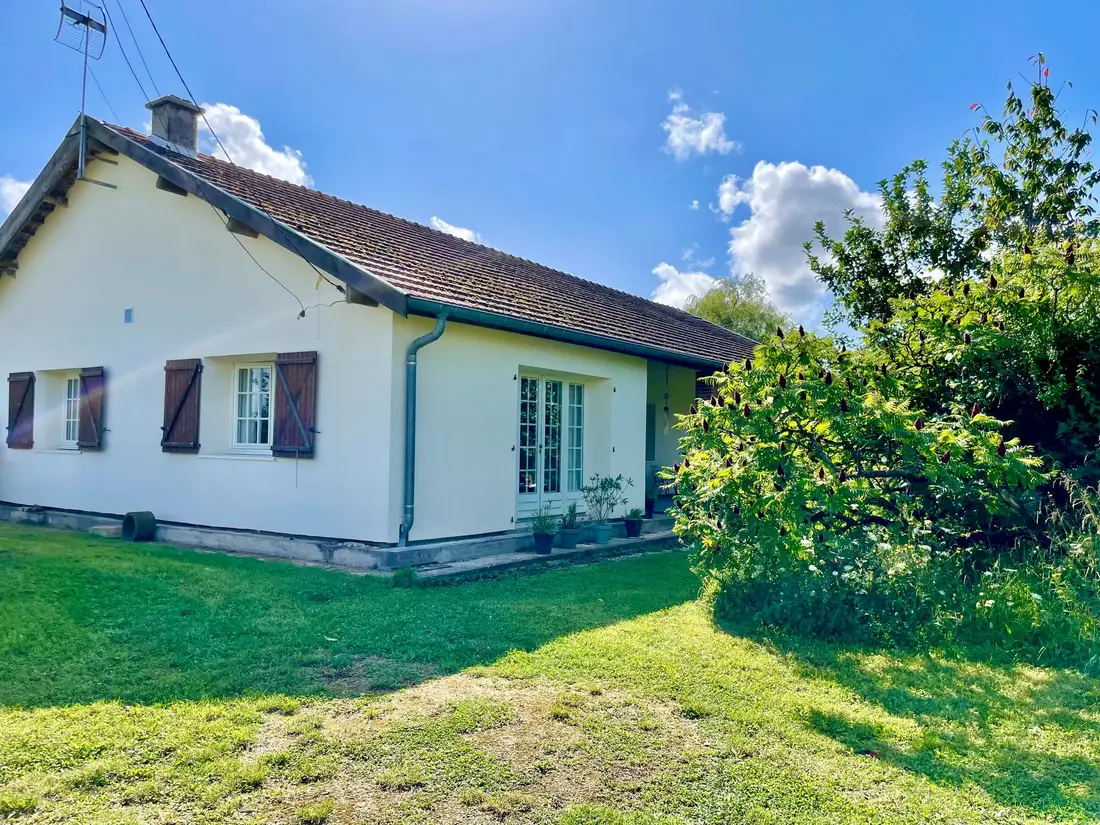 Façade de la maison de plain-pied à vendre à Charmont, volets en bois et pelouse