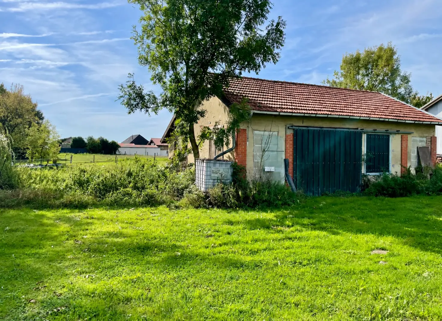 Baraquement de 75 m² avec portes vertes et toit en tuiles, sur le terrain constructible à vendre à Charmont
